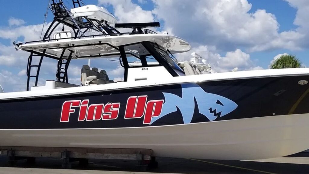 Fins Up boat with red vinyl lettering and a blue shark hull graphic