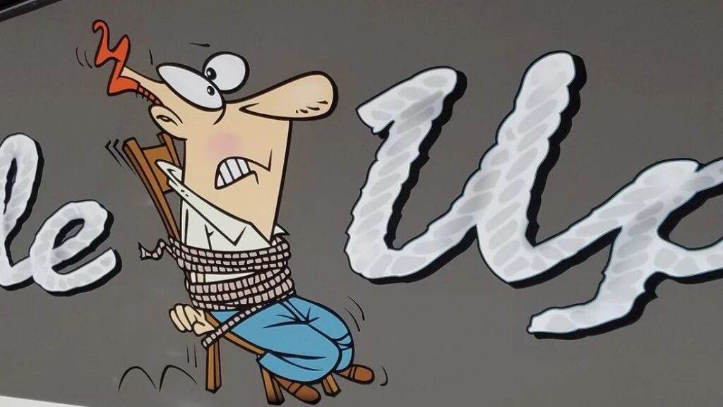 Cartoon-style custom boat graphic showing a tied-up character beside large white script lettering